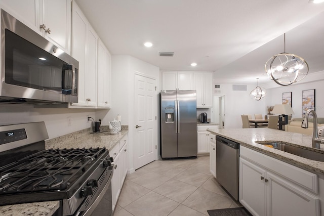 kitchen with decorative light fixtures, stainless steel appliances, white cabinetry, light stone countertops, and light tile floors