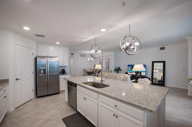 kitchen with stainless steel appliances, a center island with sink, pendant lighting, sink, and white cabinetry