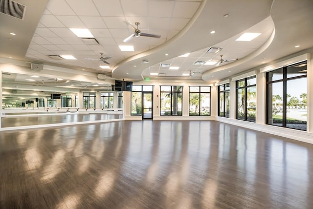 exercise room featuring plenty of natural light, ceiling fan, hardwood / wood-style flooring, and a drop ceiling