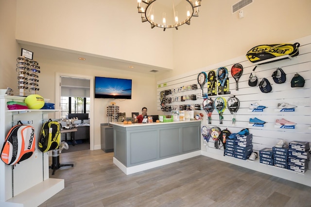 interior space with a high ceiling, gray cabinets, an inviting chandelier, and hardwood / wood-style floors