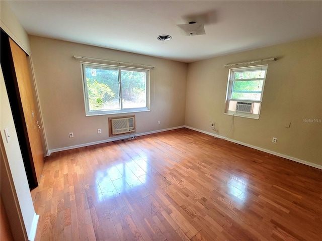 unfurnished room with a wall mounted AC and hardwood / wood-style flooring