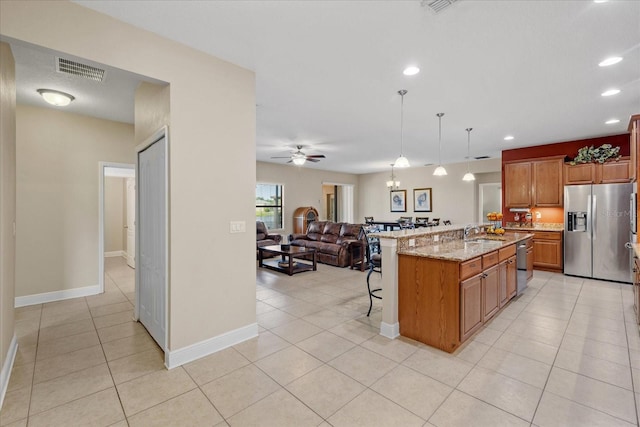 kitchen featuring hanging light fixtures, stainless steel appliances, an island with sink, a breakfast bar area, and ceiling fan