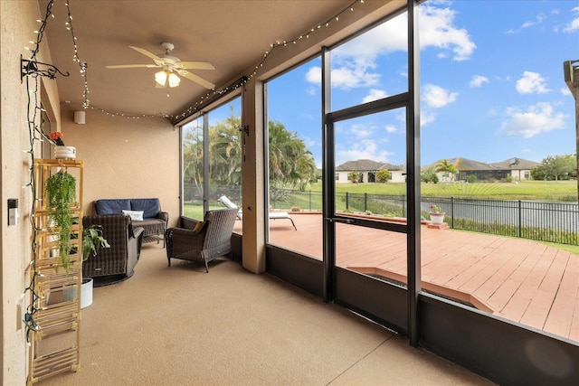 sunroom featuring ceiling fan and a water view