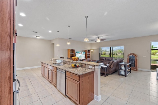 kitchen featuring decorative light fixtures, dishwasher, light stone counters, ceiling fan, and an island with sink