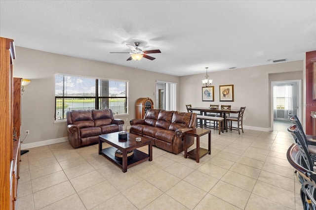 living room with ceiling fan with notable chandelier, light tile patterned floors, and a healthy amount of sunlight