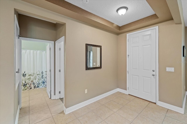 tiled entrance foyer with a textured ceiling and a raised ceiling