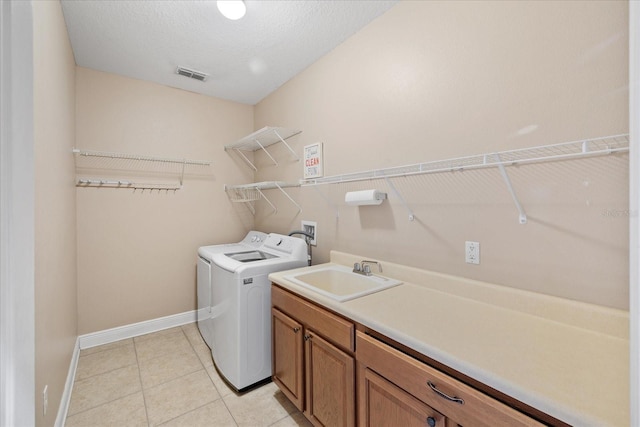 washroom with sink, a textured ceiling, cabinets, independent washer and dryer, and light tile patterned flooring