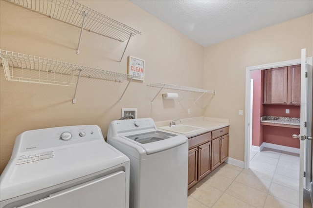 washroom featuring cabinets, independent washer and dryer, light tile patterned floors, a textured ceiling, and sink