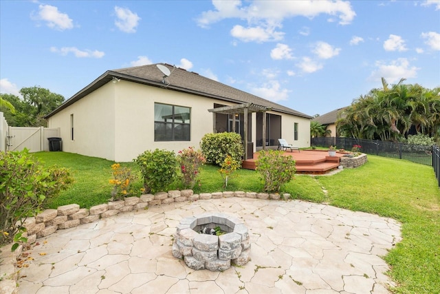 back of property featuring an outdoor fire pit, a deck, a lawn, and a sunroom