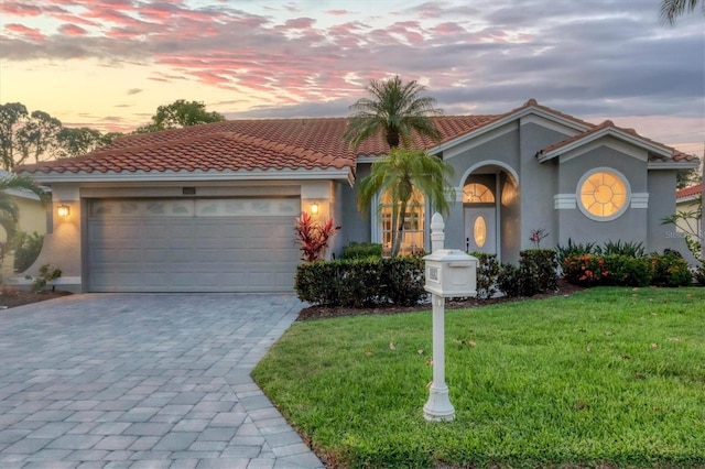 mediterranean / spanish-style house featuring a garage and a lawn