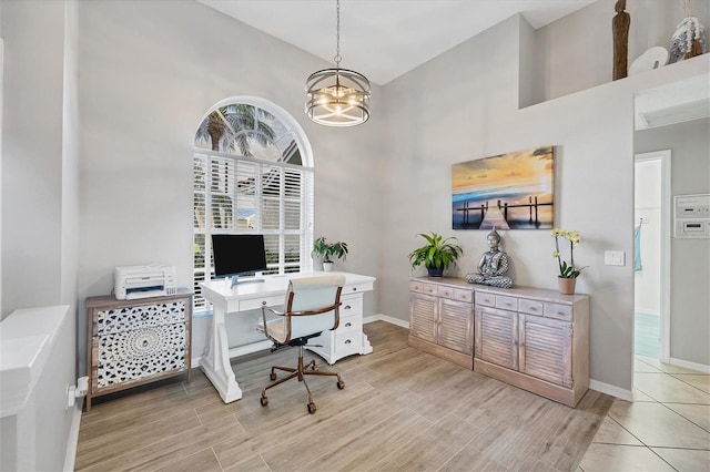 office featuring a towering ceiling, light hardwood / wood-style flooring, a wealth of natural light, and a chandelier