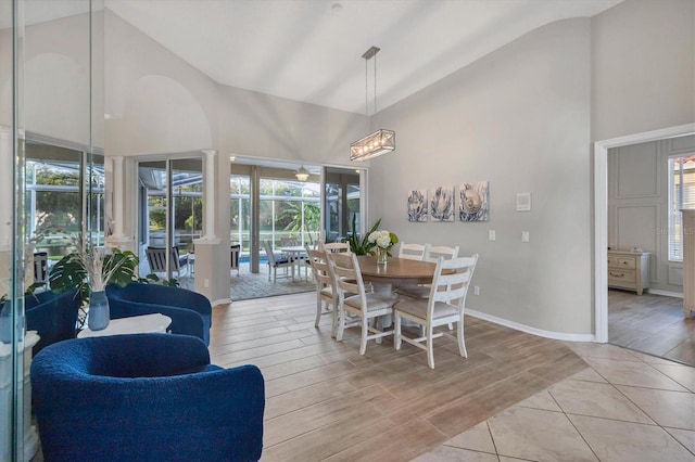 dining space with high vaulted ceiling, a healthy amount of sunlight, and light hardwood / wood-style flooring