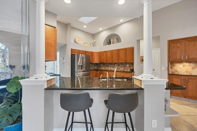 kitchen featuring sink, tasteful backsplash, stainless steel refrigerator with ice dispenser, and decorative columns