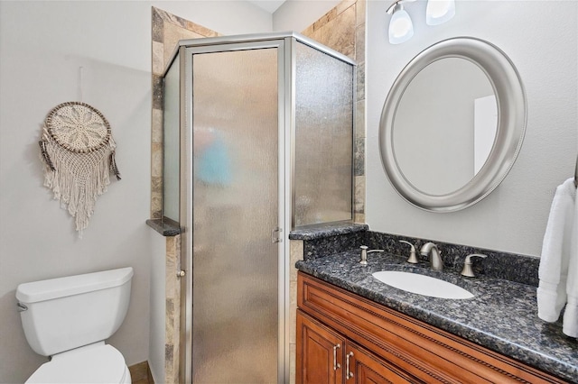 bathroom featuring vanity, toilet, and a shower with door