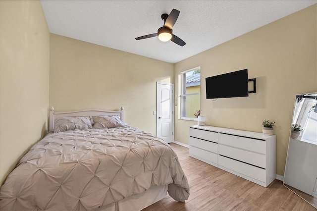 bedroom featuring ceiling fan, light hardwood / wood-style floors, and a textured ceiling