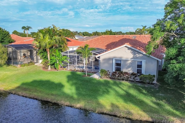 rear view of property with a lawn, glass enclosure, and a water view