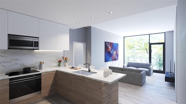 kitchen with sink, kitchen peninsula, black cooktop, oven, and white cabinets