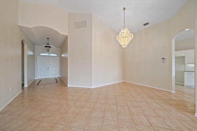 tiled empty room featuring high vaulted ceiling and an inviting chandelier