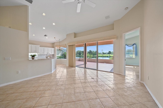 unfurnished living room featuring ceiling fan, sink, a water view, high vaulted ceiling, and light tile patterned flooring