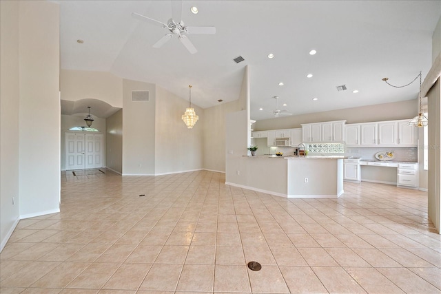 unfurnished living room featuring ceiling fan with notable chandelier, light tile patterned flooring, sink, and high vaulted ceiling