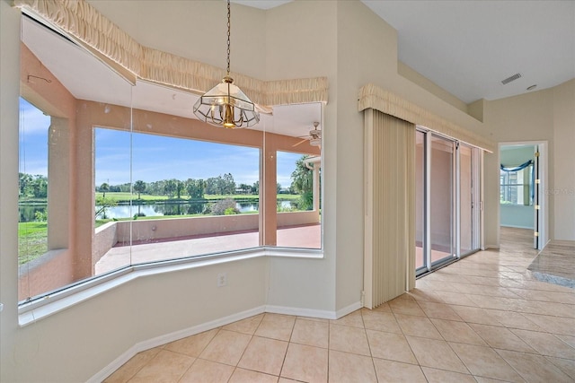 unfurnished dining area with a water view, a notable chandelier, and light tile patterned flooring