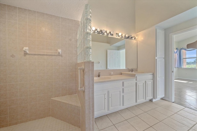 bathroom featuring tiled shower, a textured ceiling, vanity, and tile patterned floors