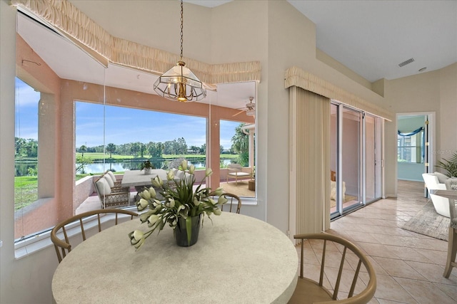 dining room featuring light tile patterned floors, a water view, and a notable chandelier