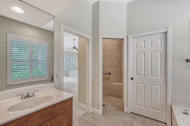 bathroom with tile flooring, a tile shower, ceiling fan, and vanity with extensive cabinet space