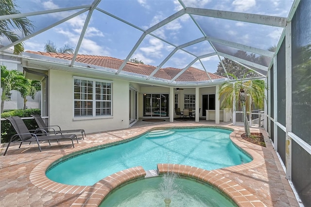 view of pool with glass enclosure, an in ground hot tub, a patio area, and ceiling fan