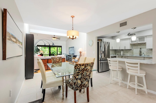 dining room with light tile patterned floors, vaulted ceiling, a notable chandelier, and sink