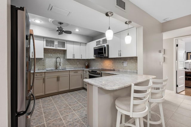 kitchen featuring a breakfast bar, backsplash, sink, appliances with stainless steel finishes, and kitchen peninsula