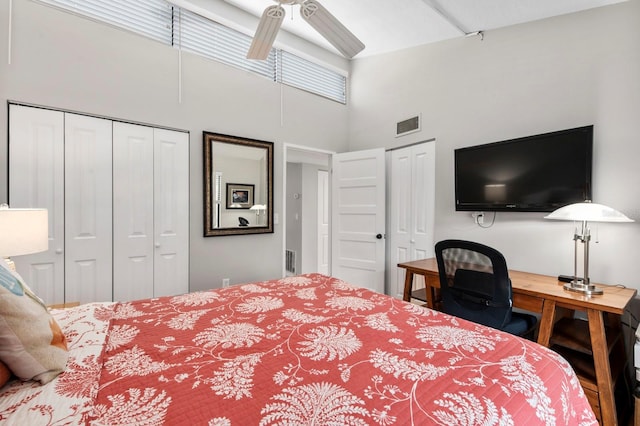 bedroom with ceiling fan, a high ceiling, and multiple closets