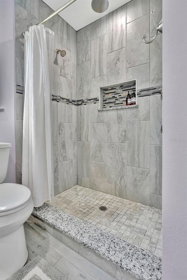 bathroom featuring tile floors, toilet, and a shower with shower curtain