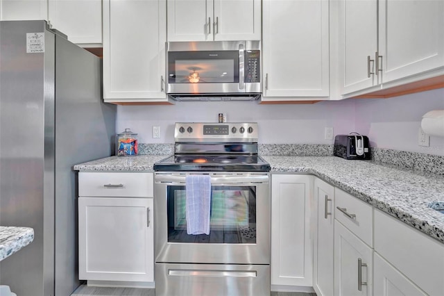 kitchen featuring white cabinetry, light stone counters, and stainless steel appliances