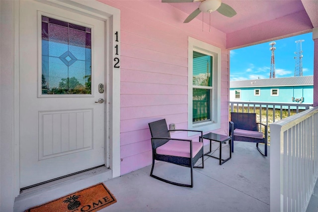 view of exterior entry with ceiling fan and a balcony