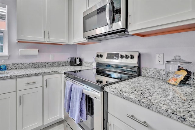 kitchen featuring light stone counters, stainless steel appliances, and white cabinets