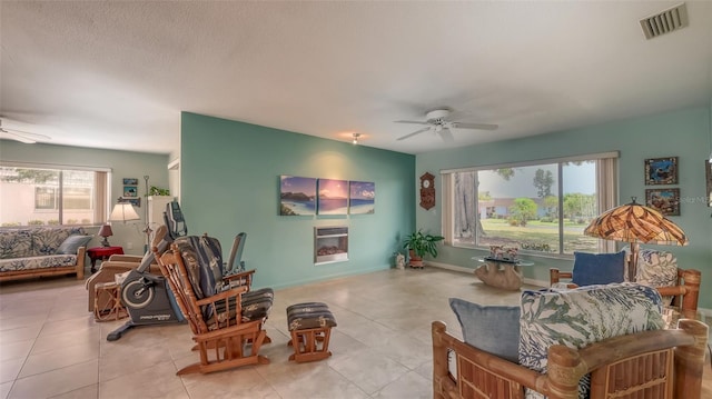 living room with tile floors, ceiling fan, and a healthy amount of sunlight