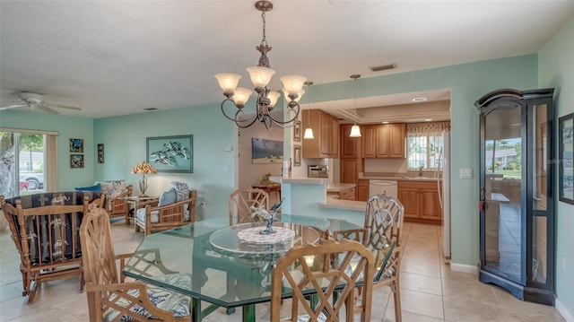 dining area with ceiling fan with notable chandelier, light tile flooring, and sink