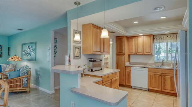 kitchen with a tray ceiling, white appliances, light tile floors, hanging light fixtures, and sink