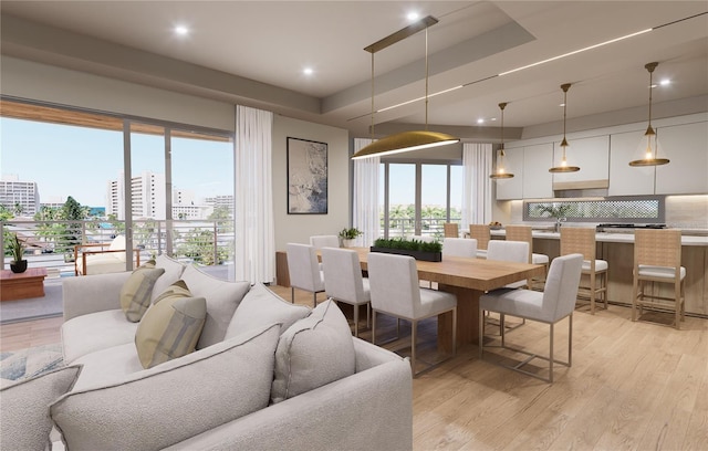 dining area featuring a healthy amount of sunlight, a tray ceiling, and light hardwood / wood-style flooring