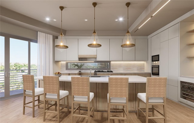 kitchen featuring white cabinets, backsplash, oven, and an island with sink