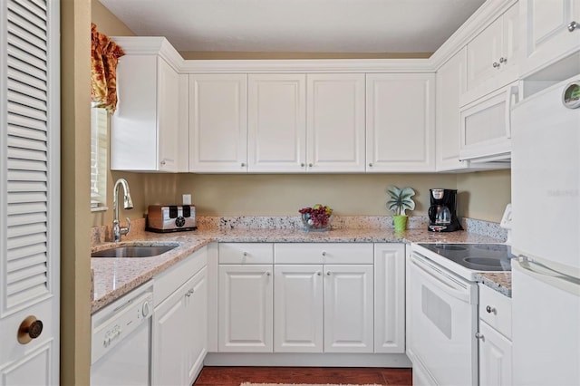 kitchen with light stone countertops, white appliances, white cabinetry, and sink