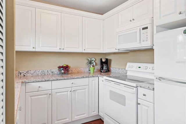 kitchen featuring white cabinets, light stone countertops, and white appliances