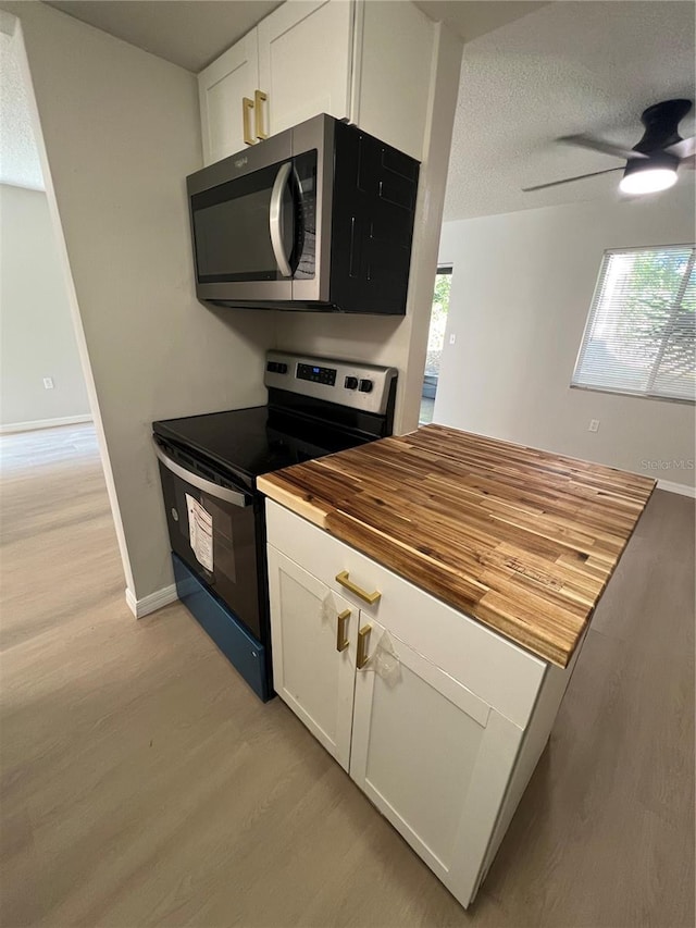 kitchen featuring ceiling fan, light wood-type flooring, wood counters, white cabinets, and appliances with stainless steel finishes