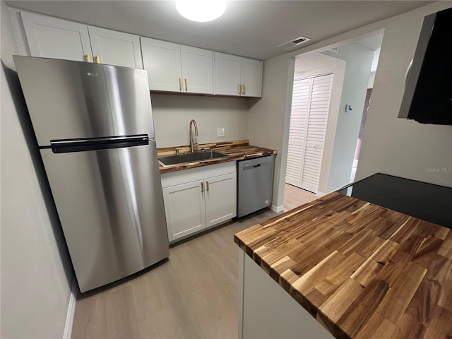 kitchen with stainless steel appliances, white cabinets, light wood-type flooring, and sink