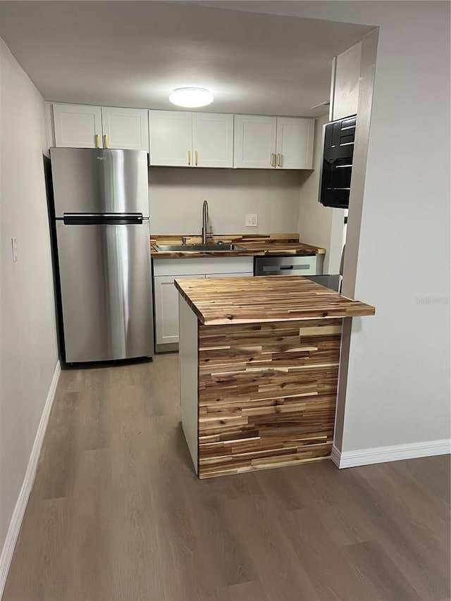 kitchen featuring wood-type flooring, white cabinetry, sink, and stainless steel fridge