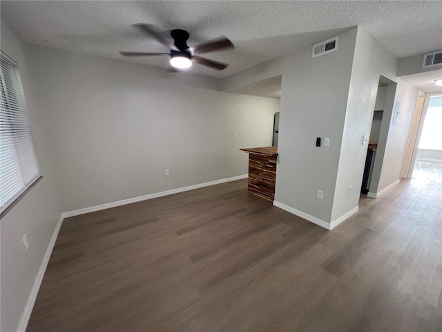 unfurnished bedroom with a textured ceiling, dark hardwood / wood-style floors, and ceiling fan