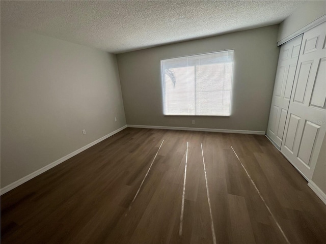 unfurnished bedroom with a closet, dark hardwood / wood-style flooring, and a textured ceiling