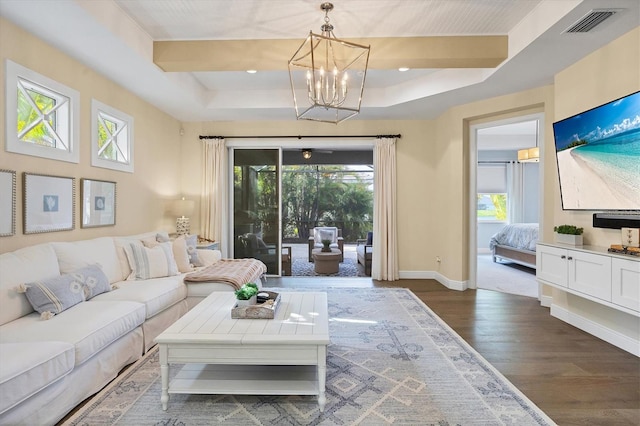 living room with dark hardwood / wood-style flooring, a raised ceiling, and a wealth of natural light