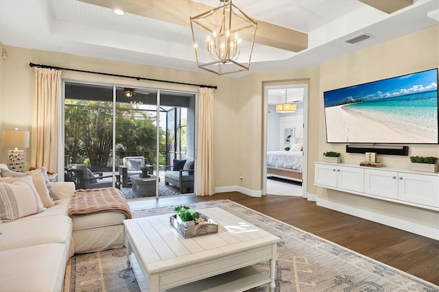 living room featuring a chandelier, dark hardwood / wood-style flooring, and a tray ceiling